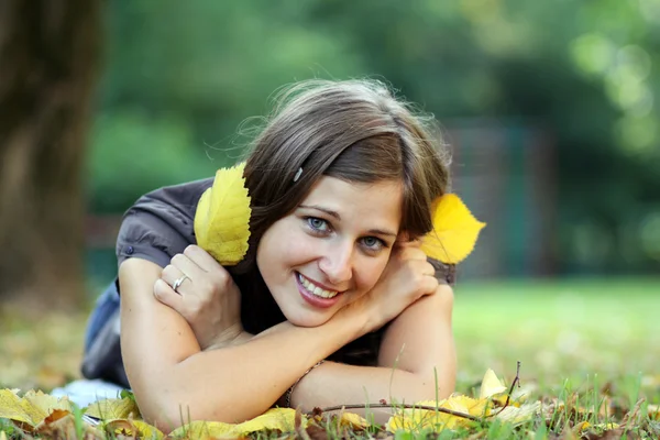 Γυναίκα που βρίσκεται σε ένα χαλί των φύλλων το φθινόπωρο πάρκο — Φωτογραφία Αρχείου