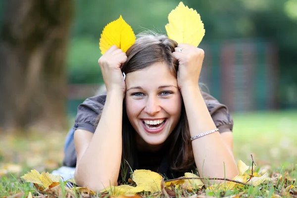 Frau liegt auf Laubteppich im Herbstpark — Stockfoto