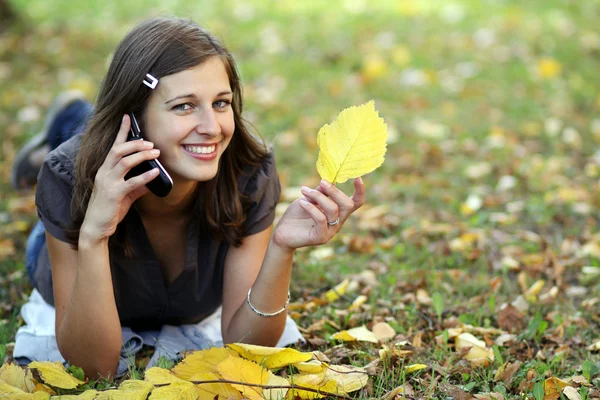 Vrouw bellen via de telefoon in de herfst park — Stockfoto