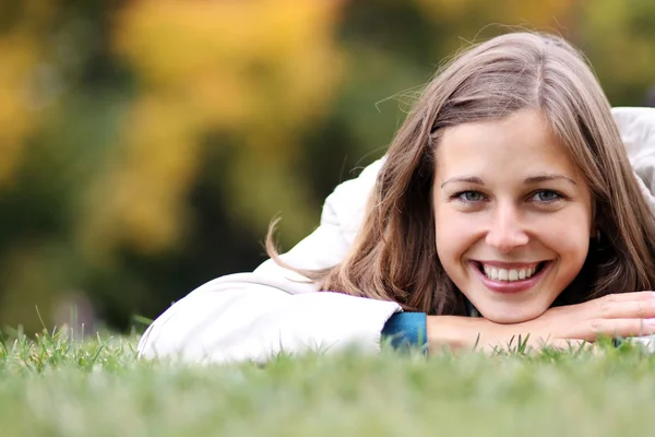 Kvinna liggande på en matta av bladen i höst park — Stockfoto