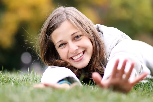 Woman lying on a carpet of leaves in autumn park — Stock Photo, Image