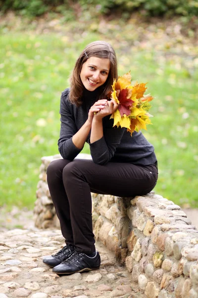 Mooie vrouw met een boeket van esdoorn bladeren — Stockfoto
