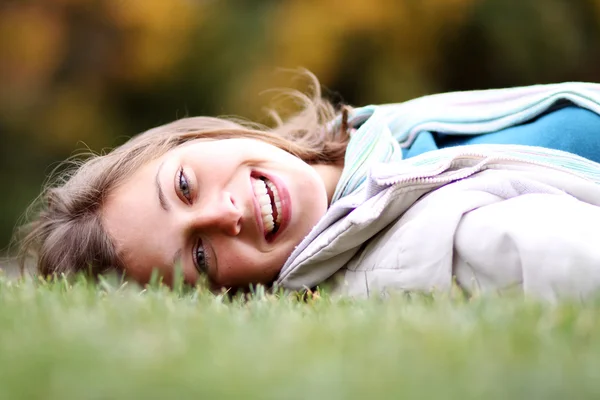 Kvinna liggande på en matta av bladen i höst park — Stockfoto