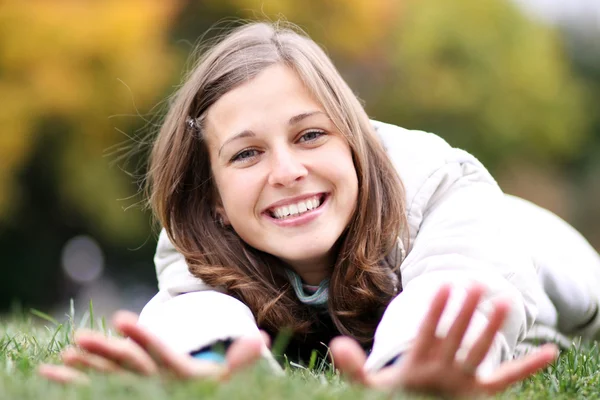 Kvinna liggande på en matta av bladen i höst park — Stockfoto