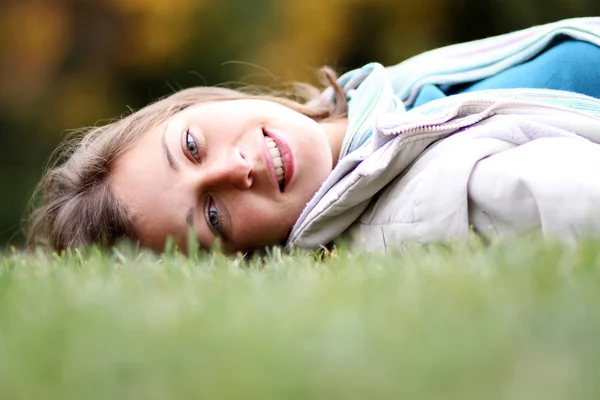 Woman lying on a carpet of leaves in autumn park — Stock Photo, Image