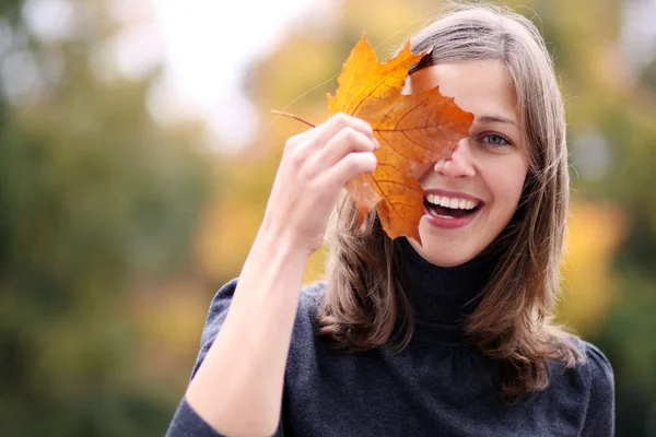 Beautiful brunette woman with golden autumn leaf — Stock Photo, Image