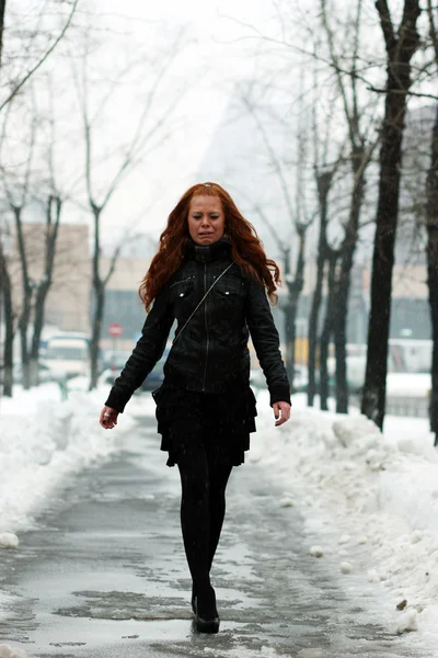 Young woman walking down snow covered street — Stock Photo, Image