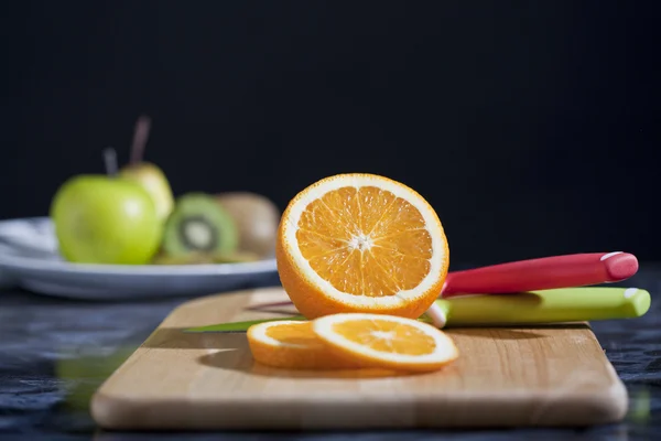 Kvinders hænder skære frisk orange på køkkenet - Stock-foto