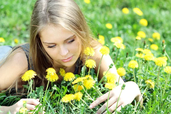 Young woman blows on a dandelion — Stock Photo, Image