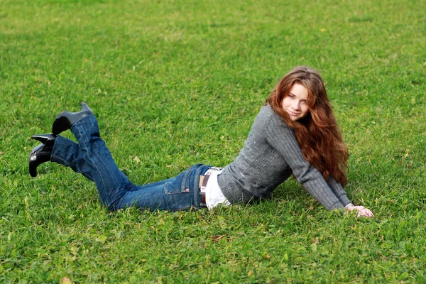 Mulher deitada em um tapete de folhas no parque de outono — Fotografia de Stock