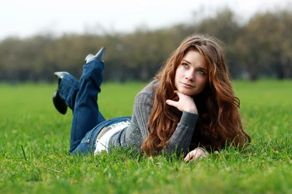 Vrouw liggend op een tapijt van bladeren in de herfst park — Stockfoto