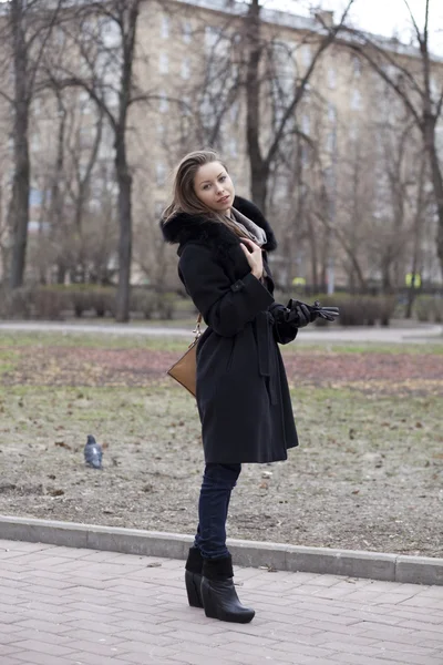 Красивая молодая женщина в черном пальто на улице — стоковое фото