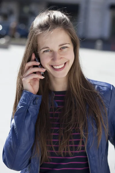 Mladá šťastná žena volá po telefonu na ulici — Stock fotografie