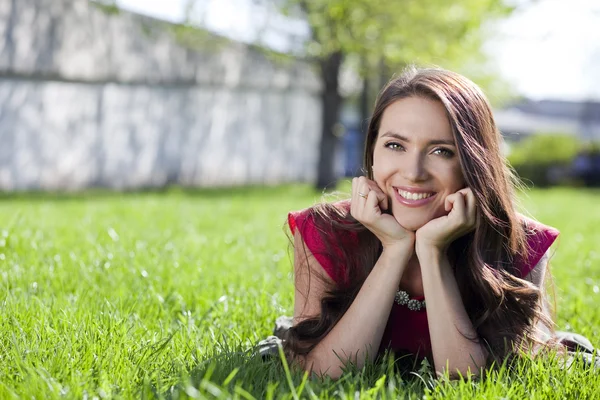 Portrait of young woman lying on a green lawn — Stock Photo, Image