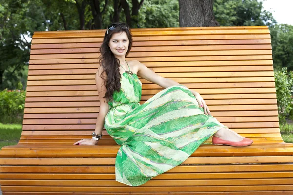 Brunette assise sur un banc dans un parc d'été — Photo