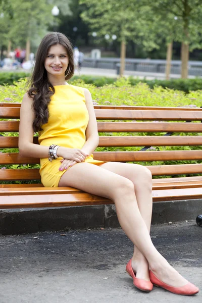 Brunette sitting on a bench in a summer park — Stock Photo, Image