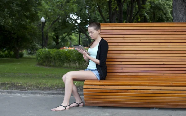 Young woman using a tablet computer on a park — Stock Photo, Image