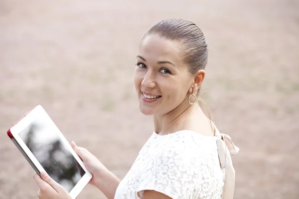 Mujer joven usando una tableta en un parque — Foto de Stock