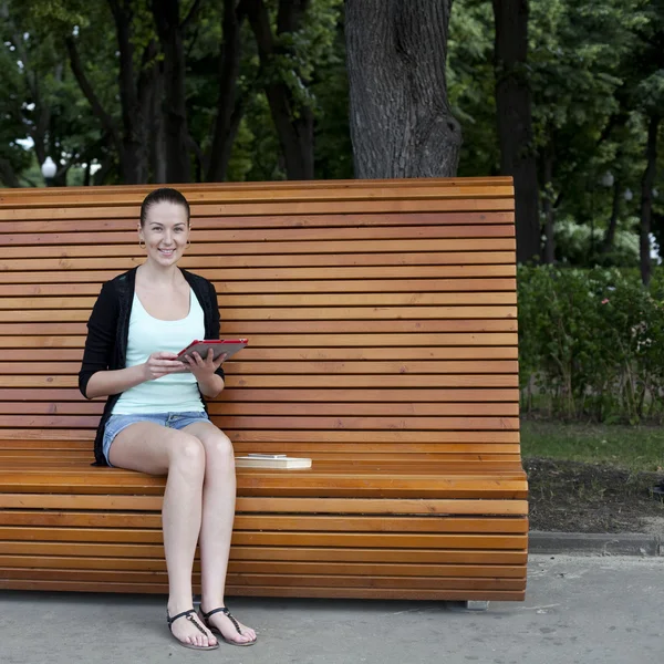 Jonge vrouw met behulp van een tablet pc op een park — Stockfoto