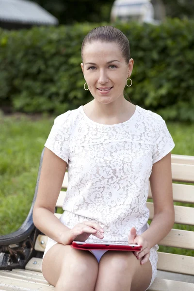 Jonge vrouw met behulp van een tablet pc op een park — Stockfoto