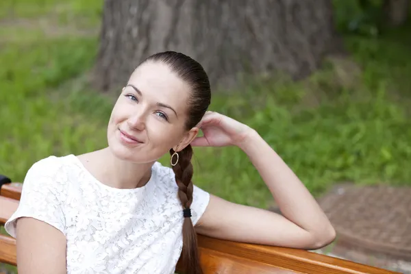 Morena sentada en un banco en un parque de verano —  Fotos de Stock