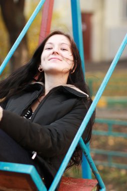 bir salıncak bir parkta otururken giyen genç kadın