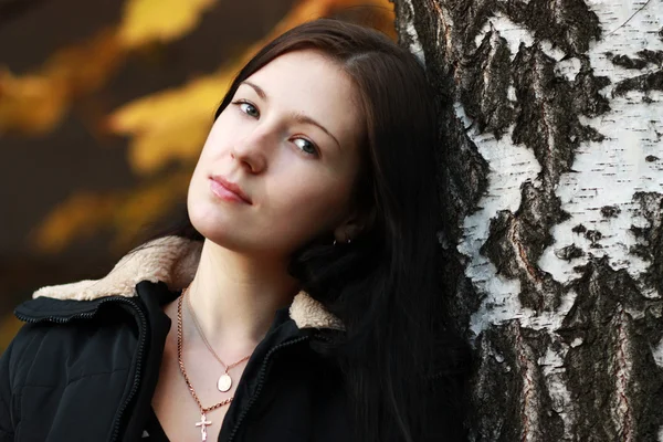 Schöne brünette Frau mit goldenem Herbstblatt — Stockfoto