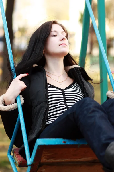 Mladá žena sedí na houpačce v parku — Stock fotografie