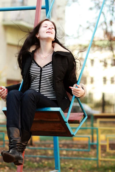 公園のブランコに座って身に着けている若い女性 — ストック写真
