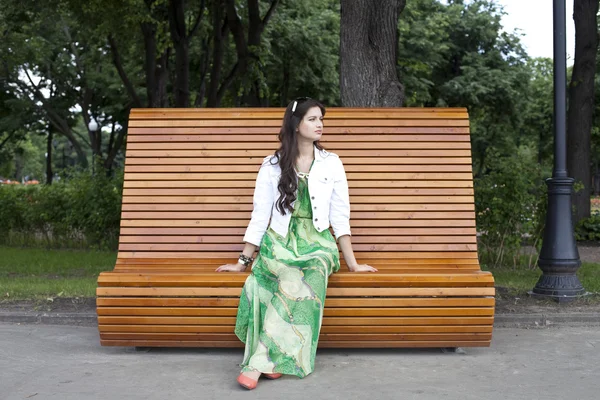 Brunette assise sur un banc dans un parc d'été — Photo