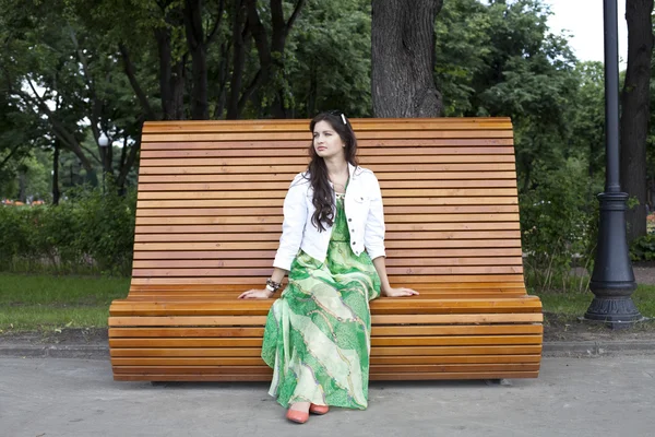 Brunette assise sur un banc dans un parc d'été — Photo