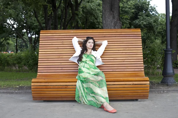 Brünette sitzt auf einer Bank in einem Sommerpark — Stockfoto