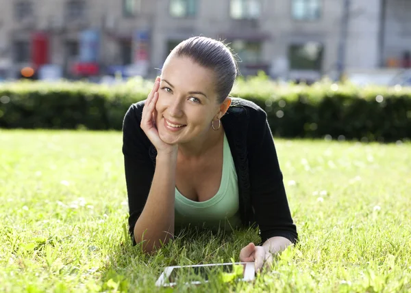 Portret van een jonge vrouw liggend op een groen gazon — Stockfoto