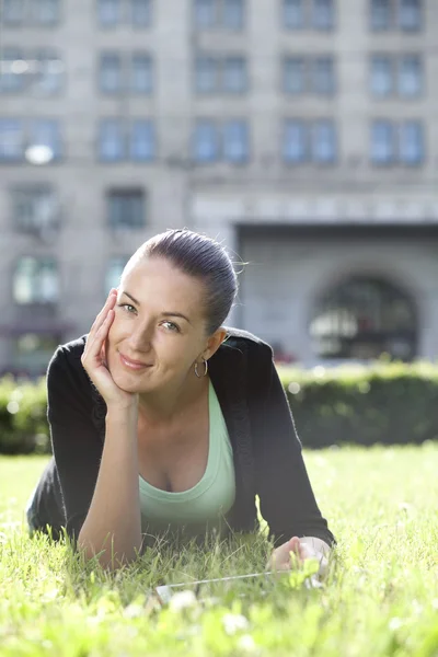 Portrait of young woman lying on a green lawn — Stock Photo, Image