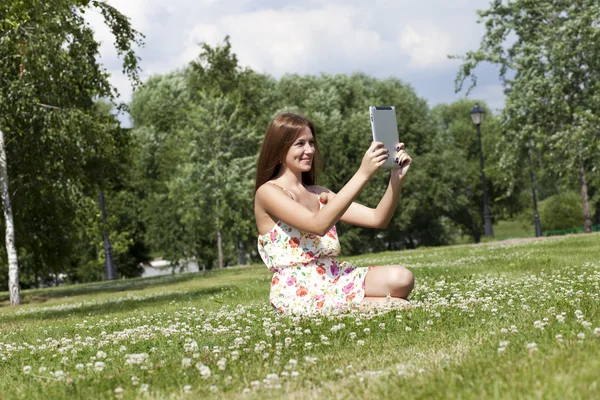 Porträtt av ung kvinna sitter på en grön gräsmatta — Stockfoto
