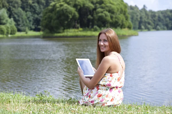 Porträtt av ung kvinna sitter på en grön gräsmatta — Stockfoto