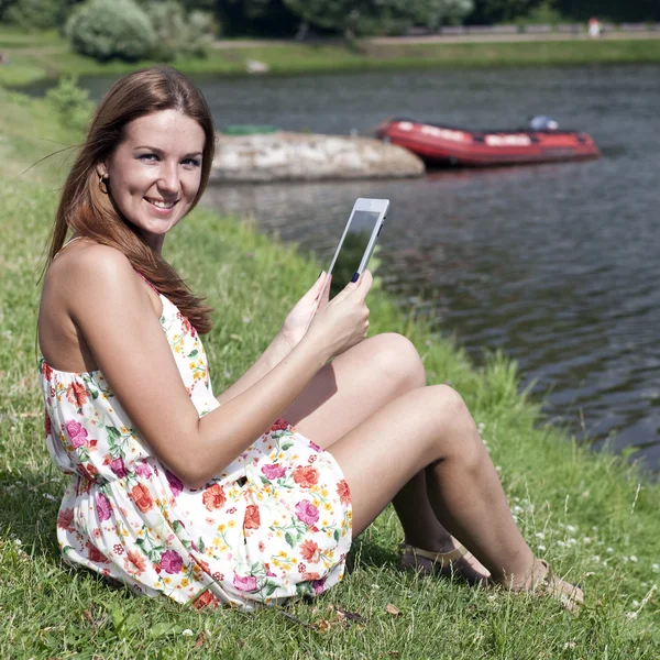 Beautiful woman sitting on a lakes shore — Stock Photo, Image