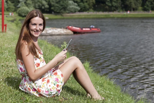 Beautiful woman sitting on a lakes shore — Stock Photo, Image