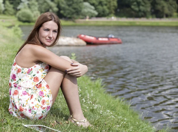 Beautiful woman sitting on a lakes shore — Stock Photo, Image
