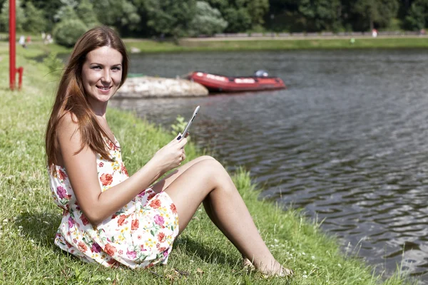 Beautiful woman sitting on a lakes shore — Stock Photo, Image