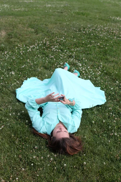 Junge Frau liegt mit Handy in der Hand im Gras — Stockfoto