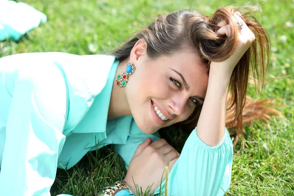 Portrait of young woman lying on a green lawn — Stock Photo, Image