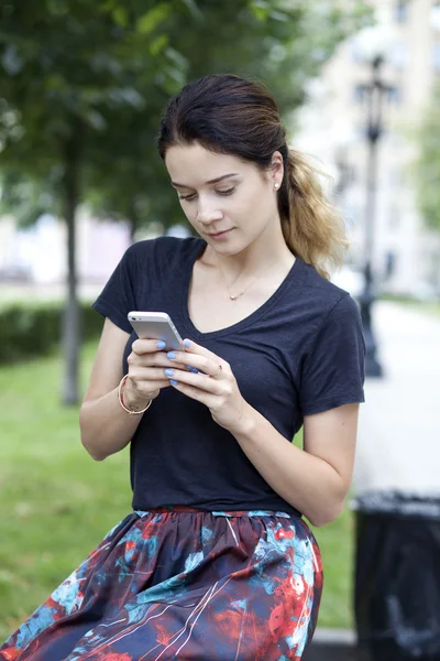 Νεαρή γυναίκα διαβάζει ένα μήνυμα στο τηλέφωνο — Φωτογραφία Αρχείου