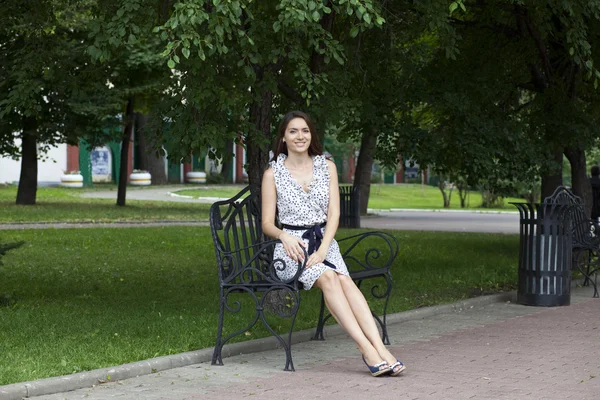 Mooie jonge vrouw zit op een bankje — Stockfoto