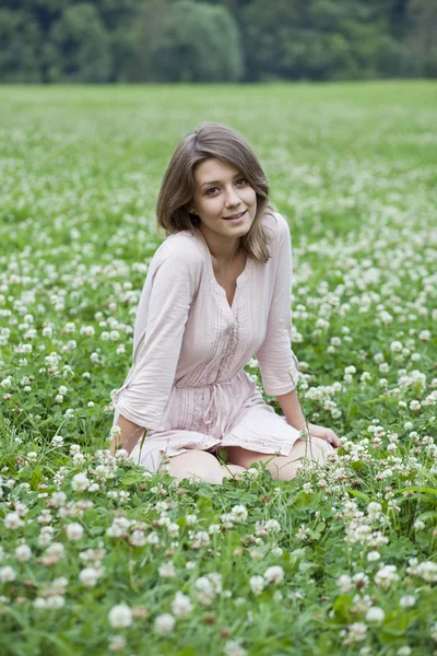 Porträtt av ung kvinna sitter på en grön gräsmatta — Stockfoto