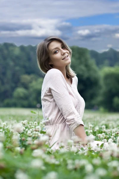 Retrato de uma jovem sentada em um gramado verde — Fotografia de Stock