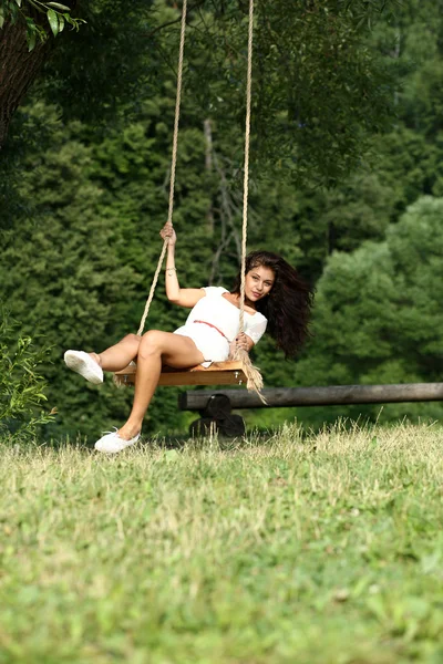 Donna felice cavalcando su un'altalena nel parco — Foto Stock