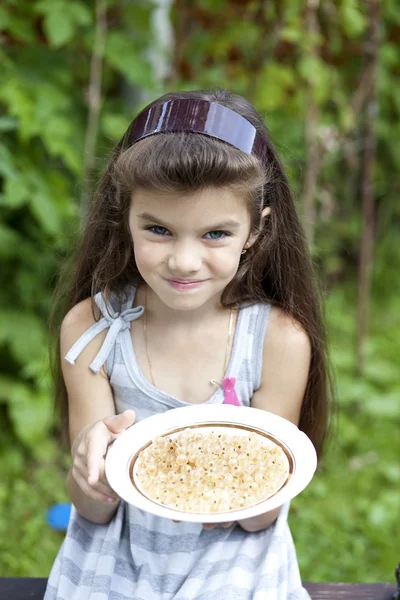 Little girl holding a plate with a white currants — Stock Photo, Image