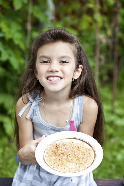 Liten flicka som håller i en tallrik med vita vinbär — Stockfoto