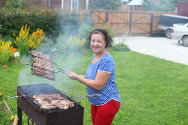 Olgun kadın bahçede Barbekü yemek
